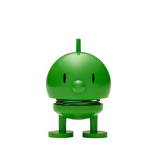 Load image into Gallery viewer, A delightful Hoptimist Bumble—a round, green toy character with roots in Danish design history—stands against a plain white background. This charming figure has a small tuft on its head, oval black eyes, and a tiny circular nose. Its cylindrical legs and spring-connected body add to its appeal as an adorable piece of home decor.
