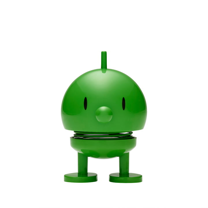 A delightful Hoptimist Bumble—a round, green toy character with roots in Danish design history—stands against a plain white background. This charming figure has a small tuft on its head, oval black eyes, and a tiny circular nose. Its cylindrical legs and spring-connected body add to its appeal as an adorable piece of home decor.