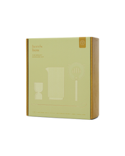 Load image into Gallery viewer, Box containing The Renley Bar Tool Set with a minimalist design. The packaging is pale green with gold accents and showcases line drawings of a pitcher, strainer, and glass. Crafted as a bar tool set in gold-plated stainless steel, the text reads &quot;here’s how&quot; and &quot;The Renley Mixology Kit.&quot; The box is closed and standing upright.
