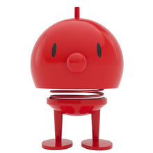 Load image into Gallery viewer, The Hoptimist Bumble is a red, round figure featuring a spring body, oval eyes, and a small nose. It stands on two flat feet and has an antenna-like top. Its simple yet playful design draws inspiration from Danish design history, offering both minimalist and cartoonish charm that makes it ideal for home decor.
