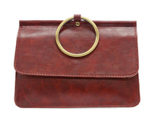 Load image into Gallery viewer, The Aria Ring Bag - Fall/Winter features a brown leather design with a large gold circular handle that resembles a bracelet bag, attached elegantly to the flap. Its textured finish and visible stitching enhance its minimalist elegance, making it an ideal accessory for both casual and formal occasions, effortlessly blending style with versatility.
