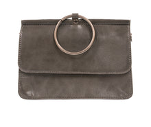 Load image into Gallery viewer, The Aria Ring Bag - Fall/Winter is a brown vegan leather clutch featuring a large silver metal ring on top. It boasts a smooth texture with a fold-over flap, embodying minimalist design with clean lines. The elegance of this bracelet bag shines through without any visible branding or embellishments.
