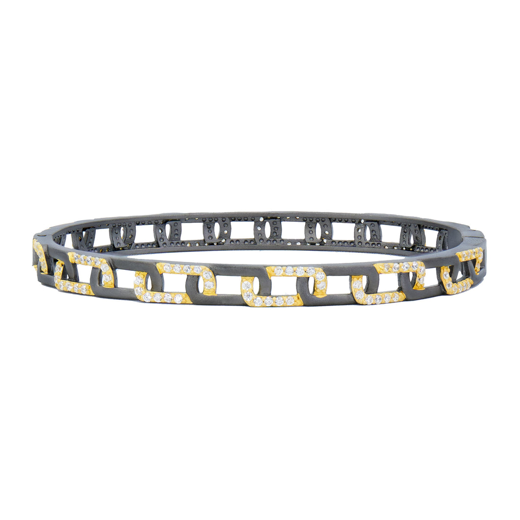 The Signature Grit Chain Link Pave Thin Hinge Bangle showcases a circular chain link design with a dark metal base and an intricate linked pattern. The gold links, embellished with clear cubic zirconia stones, alternate between horizontal and vertical orientations, highlighting the elegant contrast between the dark base and the sparkling gold links.