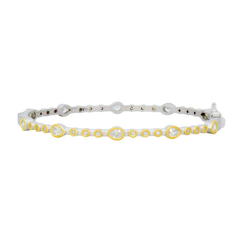 The Teardrop Station Hinge Bangle is a sleek and elegant bracelet displaying alternating pear-shaped and round white diamonds in yellow gold bezels, all set on a white gold band. It beautifully combines modern and classic design elements.