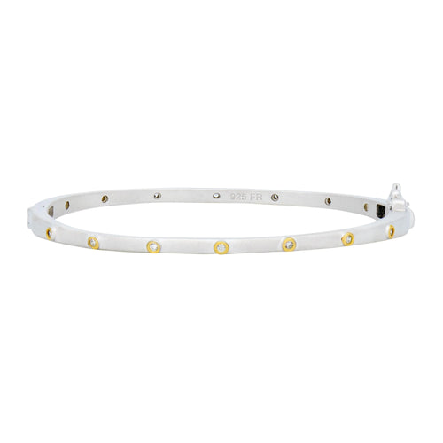 The Thin Bezel Stacking Bangle is a silver circular bracelet adorned with small, round yellow and white gemstones that mimic the look of cubic zirconia stones, evenly spaced along its surface. The inside is engraved with 