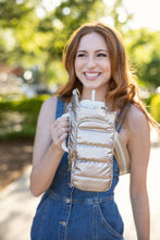 Load image into Gallery viewer, A woman with long reddish hair is outdoors, smiling as she dons a blue denim sleeveless outfit. She&#39;s holding a white tumbler equipped with a straw that&#39;s secured using an elastic holder, and it&#39;s protected by a HydroBag HANDLE that features a handy zipper pocket. The surrounding background showcases lush greenery and softly blurred lights.
