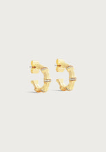 Load image into Gallery viewer, The Bamboo Huggie Hoop Earrings exude a chic style with their textured bamboo-inspired design and delicate sparkling stones adorning the edges. Made from gold-plated brass, these earrings boast a shiny finish, beautifully contrasted against a plain, off-white background.
