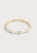 Load image into Gallery viewer, The Bamboo Enameled Hinge Bangle is an elegant bracelet crafted from 18k gold-dipped brass, featuring a bamboo-inspired design with smooth white enamel sections. Subtle engraved details near the joints and a polished finish enhance its sophistication, beautifully contrasted against a light grey background.
