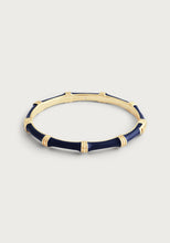 Load image into Gallery viewer, The Bamboo Enameled Hinge Bangle is a circular bracelet with alternating navy blue and 18k gold-dipped brass segments. It features smooth blue sections bordered by shimmering gold bands, and the interior is engraved with &quot;ANNABELLE ATAMI,&quot; set against a light grey background.
