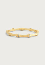 Load image into Gallery viewer, The Bamboo Hinged Bangle is exquisitely designed with smooth, curved segments that are embellished with sparkling crystals. The engraving of &quot;Anabel Aram&quot; on the inside adds a special touch, and it is crafted from 18k gold-dipped brass, offering a luxurious contrast against the soft, light gray background.
