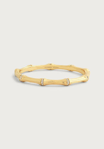 The Bamboo Hinged Bangle - Gold features a bamboo segment design in 18k gold-dipped brass with a smooth finish. Two segments sparkle with diamonds, and the interior reads 