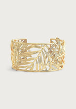 Load image into Gallery viewer, Introducing the Palm Leaves Cuff: a gold cuff bracelet featuring an openwork leaf pattern adorned with hand-set crystals. Its design intricately weaves leaves together, resulting in a delicate and elegant appearance. Crafted from 18K gold-plated brass, the shiny finish elevates its luxurious look.
