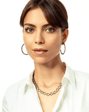 Load image into Gallery viewer, A woman with dark hair tied back wears a white blouse, her neutral expression framed by Teardrop Hoop Earrings in mixed metal. A chunky chain necklace adds depth to her look as she faces the camera against a plain white background.
