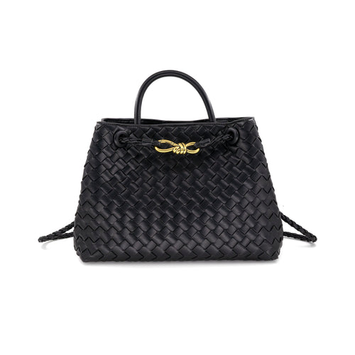 The image showcases the Talene Crossbody Bag, a black woven leather handbag with a structured design. It includes a short handle, gold-toned hardware, an intricate knot detail on the front, and a magnetic closure for added convenience. The bag exudes sophistication and timeless style.