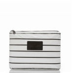 The Aloha Pouches are rectangular white zippered pouches with horizontal black stripes and a black patch in the center. Ideal for organizing toiletries while traveling, they feature a top zipper with a metal pull, offering minimalistic design and functionality for inflight organization.
