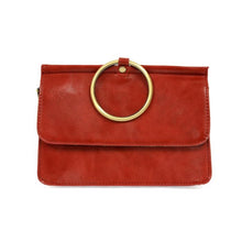 Load image into Gallery viewer, Introducing the Aria Ring Bag - Fall/Winter edition: a chic clutch crafted from smooth red vegan leather. This stylish piece features a striking large gold circular ring on the front flap, enhanced by its minimalist design and visible edge stitching. It also includes an optional crossbody strap for added versatility in its modern appearance.
