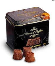 Load image into Gallery viewer, A sleek, rectangular metal tin labeled &quot;Dream of Truffles&quot; with gold swirls and sea salt truffle images holds 200g of gourmet indulgence. The luxurious black tin featuring Cocoa Dusted Truffles exudes gift-worthy allure beside irresistibly beckoning caramel truffles.
