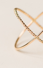 Load image into Gallery viewer, Close-up of a delicate Braided X Ring on a soft beige background. This 14k gold-filled handcrafted ring features a minimalistic design with twisted detailing and overlapping bands, creating an elegant, interconnected pattern. The lighting highlights the shiny, polished texture of the metal.
