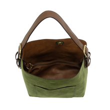 Load image into Gallery viewer, The Hobo 2 in 1 Faux Suede Handbag showcases a green vegan leather exterior paired with a brown interior and handle. Key features include a central zippered compartment, button clasp, front pocket, and a removable crossbody strap. The open view reveals a spacious interior, enhanced by the light glinting off the fabric.
