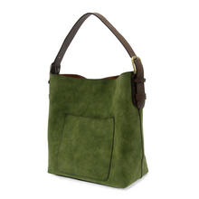 Load image into Gallery viewer, The Hobo 2 in 1 Faux Suede Handbag is a green faux suede bag with a large front pocket and an adjustable brown vegan leather shoulder strap with a brass buckle. It features a rectangular shape, smooth finish, and slightly slouched appearance.
