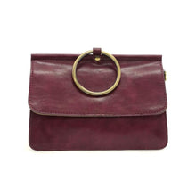 Load image into Gallery viewer, The Aria Ring Bag - Fall/Winter is a burgundy leather clutch featuring a fold-over flap and a prominent gold circular handle, giving it the appearance of a bracelet bag. It has a smooth texture and showcases a minimalist design, with neatly stitched edges that highlight its clean lines and elegant style.
