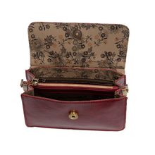 Load image into Gallery viewer, The Aria Ring Bag - Fall/Winter features a red vegan leather exterior with an open flap design, revealing a floral-patterned interior lining. Inside, it includes a zippered compartment complemented by open sections. The gold magnetic snap closure enhances its elegance, and the detachable shoulder strap provides versatile styling for any occasion.
