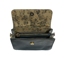 Load image into Gallery viewer, The Aria Ring Bag - Fall/Winter includes a smooth dark leather exterior and features a floral-patterned inner lining adorned with subtle leaf and flower motifs. It comes with a detachable shoulder strap and has a central zippered compartment flanked by two open sections, all secured by a brass button clasp on the flap.
