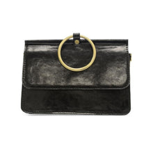 Load image into Gallery viewer, The Aria Ring Bag - Fall/Winter is a sleek black leather clutch with a glossy finish, highlighted by a large gold ring serving as the top handle above the flap closure. This minimalist bracelet bag features the ring as its distinctive focal point, and its texture is smooth and polished.
