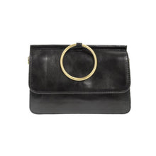 Load image into Gallery viewer, The Aria Ring Bag - Fall/Winter is a black vegan leather clutch with a smooth texture and a prominent large gold ring handle on the flap. It features a sleek and minimalist design, complete with a front flap closure, while the gold ring enhances its sophisticated bracelet bag look.
