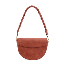 Load image into Gallery viewer, Introducing the Luna Crescent Crossbody with Braided Handle, a stylish, rust-red half-moon bag featuring a smooth vegan suede leather texture and a front flap that folds over. Its braided shoulder strap is elegantly attached with gold-tone metal clasps, adding sophistication to its simple design against a plain white background.
