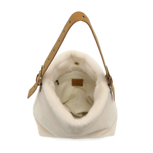 Load image into Gallery viewer, The Teresa Faux Fur Hobo is a small, open bag crafted from white faux fur, offering a soft and fuzzy exterior. It includes an adjustable shoulder strap made of brown vegan leather with metal buckles on each side. Inside, you&#39;ll find a light fabric lining along with a small leather tag on the inside back wall.
