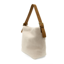 Load image into Gallery viewer, The Teresa Faux Fur Hobo is a soft-textured, white handbag made from vegan leather, featuring a straightforward design with a brown strap and adjustable metal buckles. Its boxy shape emphasizes its minimalist aesthetic, and it is set against a plain white background.
