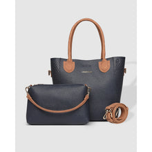 Load image into Gallery viewer, Featuring the Dublin Tote Bag, this stylish handbag set includes a large navy tote with tan handles and a smaller navy crossbody bag. The crossbody is made from textured vegan leather and comes with a detachable tan strap. Both bags are beautifully displayed against a plain gray background.
