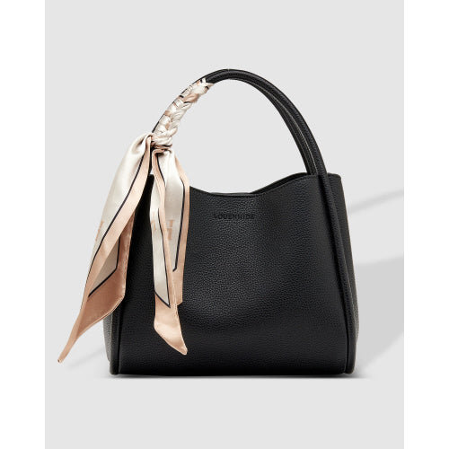 The Steffie Mini Tote Bag is a chic black handbag made from vegan leather, showcasing a sleek, curved design with a structured silhouette. The handle is adorned with a silky scarf in beige and brown patterns, enhancing its elegance. It features a subtle texture against a simple light gray background.