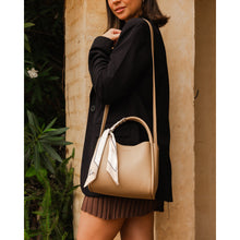 Load image into Gallery viewer, A person in a black blazer and brown skirt stands against a textured wall. They carry the chic Steffie Mini Tote Bag with a white scarf tied to its handle. Lush green leaves are visible on the left, adding a natural element to the scene.
