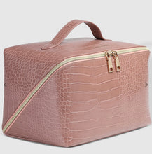 Load image into Gallery viewer, The Coordinating Toiletry and Makeup Case, crafted from pink faux crocodile leather, boasts a gold zipper with two pulls for easy access. Its top handle ensures convenient carrying, while it rests against a plain white background to emphasize its textured surface and structured design—ideal for organizing your essentials.
