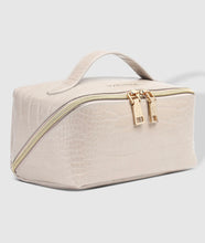 Load image into Gallery viewer, A beige Coordinating Toiletry and Makeup Case with a faux croc finish, featuring gold zippers and a top handle. This stylish accessory boasts a structured rectangular shape with embossed details. When slightly opened, it reveals two metallic zipper pulls and the brand logo subtly imprinted near the handle.
