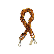 Load image into Gallery viewer, The Faux Tortoise Shell Lucite Cluster Chain Strap is designed for handbags, featuring large, glossy links in a tortoiseshell pattern. Metal clasps are attached at the ends for easy attachment, with one clasp adorned by a small rectangular tag. The chain lays coiled in a loose, overlapping fashion against a plain white background.
