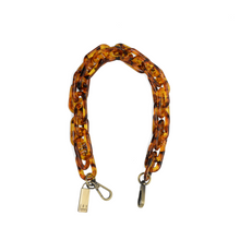 Load image into Gallery viewer, A Faux Tortoise Shell Lucite Cluster Chain Strap designed as a bracelet with a circular arrangement. It includes two metallic clasps for fastening and features a small, rectangular metal tag near one clasp inscribed with &quot;J.W.&quot; Ideal for those looking for an updated accessory that reflects the sophistication of designer handbags.
