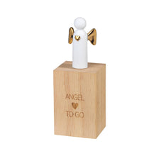 Load image into Gallery viewer, The Porcelain Gift in Wood Box features a small standing angel figurine with gold wings and a gold heart on its chest, perched atop a wooden block that resembles an antique wood box. The block is engraved with the text &quot;ANGEL ♥ TO GO,&quot; and the angel has a simplistic design with a white, featureless body and head.
