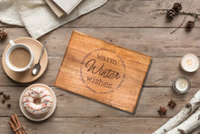 Load image into Gallery viewer, An Engraved Board embellished with &quot;Warm Winter Wishes&quot; and encircled by festive words is positioned on a rustic table. Alongside, there&#39;s a cup of coffee, a donut topped with sprinkles, candles, pinecones, and star anise. A white textured cloth and sheets of parchment enhance the cozy winter ambiance.
