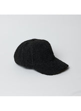 Load image into Gallery viewer, The Sherpa Cap, featuring a textured black design and curved brim, is positioned slightly to the left against a plain, light gray background. Its sherpa-like surface makes it a distinctive addition to fall and winter fashion with its cozy, tactile appearance.
