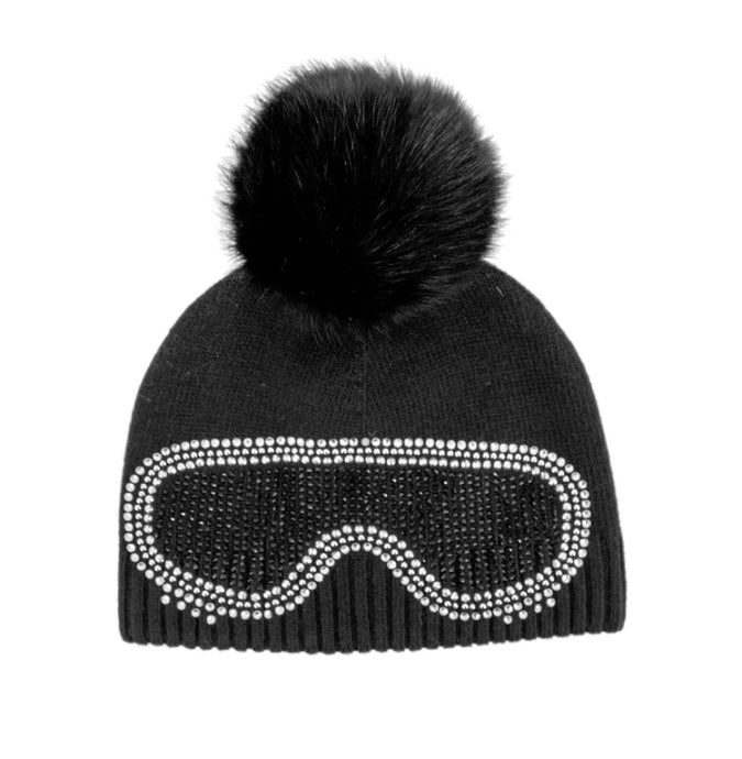 The Knit Beanie with Crystal Ski Goggles & Fox Fur Pom-Pom showcases a striking black design, highlighted by a large fox fur pom-pom on top. The front is adorned with sparkling rhinestone embellishments in the shape of ski goggles, offering both charm and fun. A ribbed texture along the bottom edge guarantees a secure and comfortable fit.