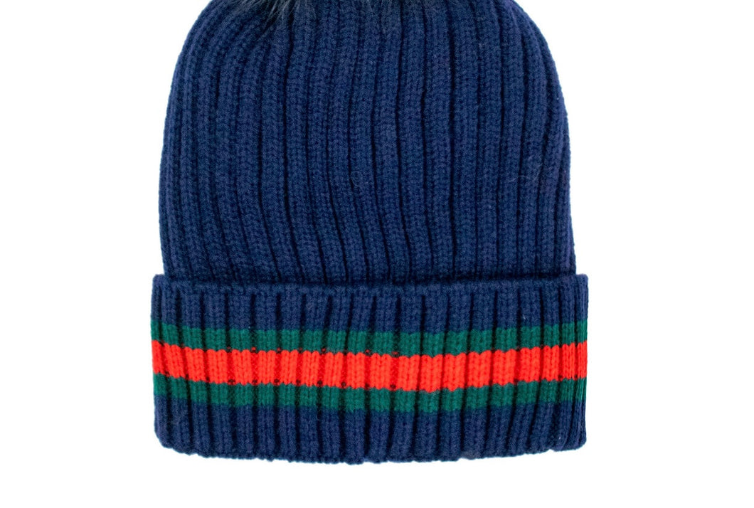 Displayed against a white backdrop is the Knit Hat with Striped Cuff, featuring a ribbed navy blue design. The folded cuff showcases horizontal red and green stripes, lending it a cozy appearance that makes it perfect for cold weather.