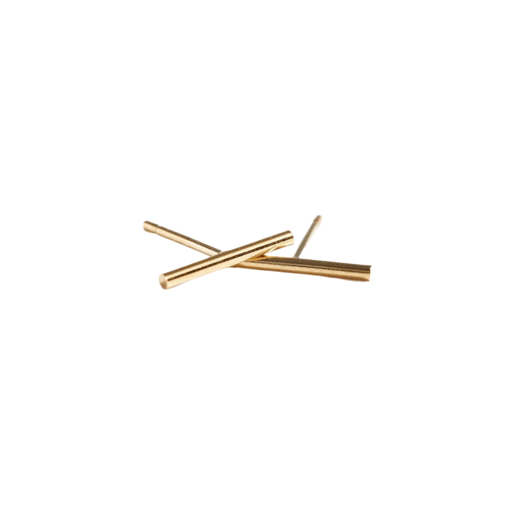 A pair of Stick Studs, minimalist in design, are crossed in an "X" shape against a plain white background. The sleek gold bars are smooth and shiny, accentuating their modern and elegant style, making them perfect for those who value ethical fashion and appreciate handmade jewelry.