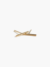 Load image into Gallery viewer, A pair of Stick Studs, minimalist in design, are crossed in an &quot;X&quot; shape against a plain white background. The sleek gold bars are smooth and shiny, accentuating their modern and elegant style, making them perfect for those who value ethical fashion and appreciate handmade jewelry.
