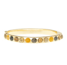 Load image into Gallery viewer, The Semi Precious Stone Bangle, in a gold-colored design, showcases semi-precious stones in black, beige, and yellow. Each polished stone is arranged in a seamless pattern along the band with a circumference of 6 1/4 inches. The interior of the bangle is smooth and reflective.
