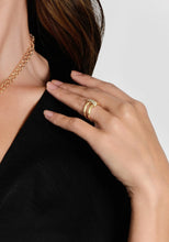 Load image into Gallery viewer, A person in a black top is captured from the neck to the hand, showcasing a layered gold necklace and an Enchanted Forest Chain Double Ring on their ring finger. The double rings are embellished with small, sparkling crystals. The person&#39;s hair is partially visible, flowing over their shoulder against a plain, light-colored background.
