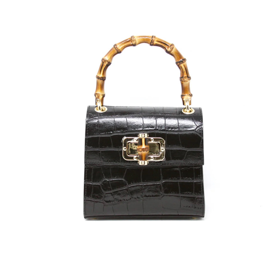 The Leather Bag With Bamboo Handle boasts a glossy black crocodile-textured Italian leather exterior, a bamboo handle, and a gold-detailed front clasp. Set against a white background, it highlights its structured elegance.