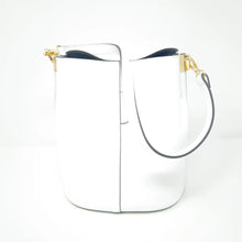 Load image into Gallery viewer, The Leather Bucket Bag is crafted from Italian leather and features a single shoulder strap with elegant gold hardware, including two clasps. It has a smooth finish, and its interior is lined in a dark hue against a plain white background.
